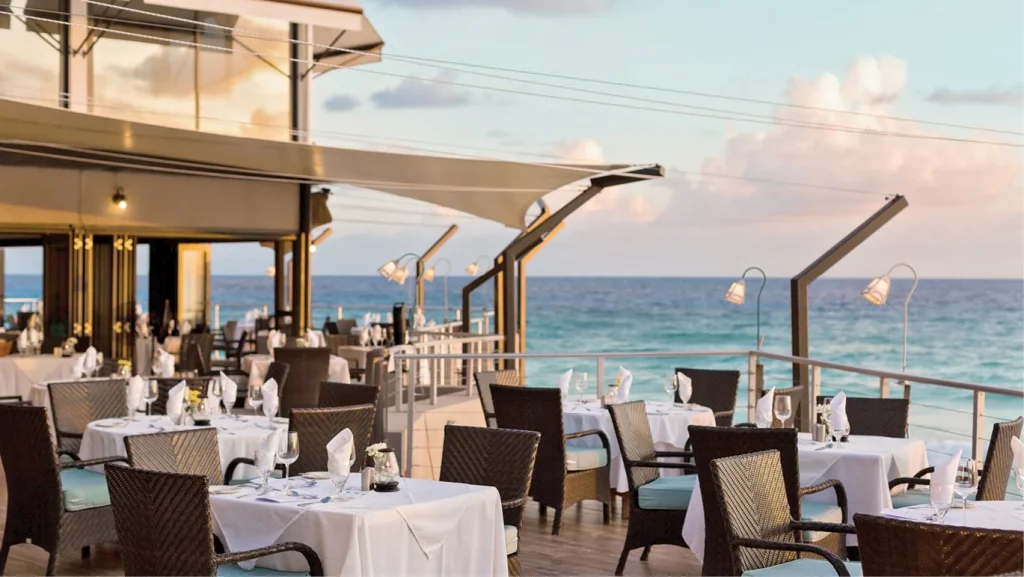restaurant overlooking the sea with tables and chairs at sunset