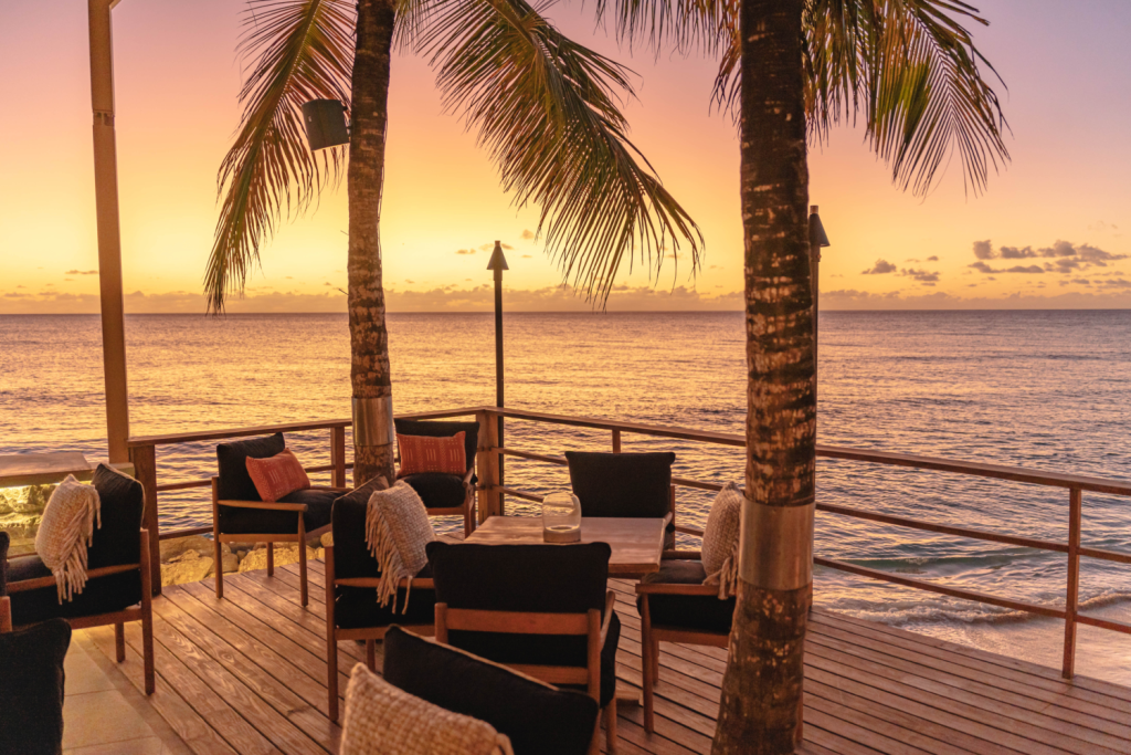 sunset background with comfy chairs on deck in between two palm trees
