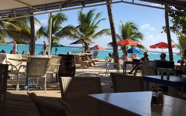 beach bar on the beach with sun shades and chairs around tables