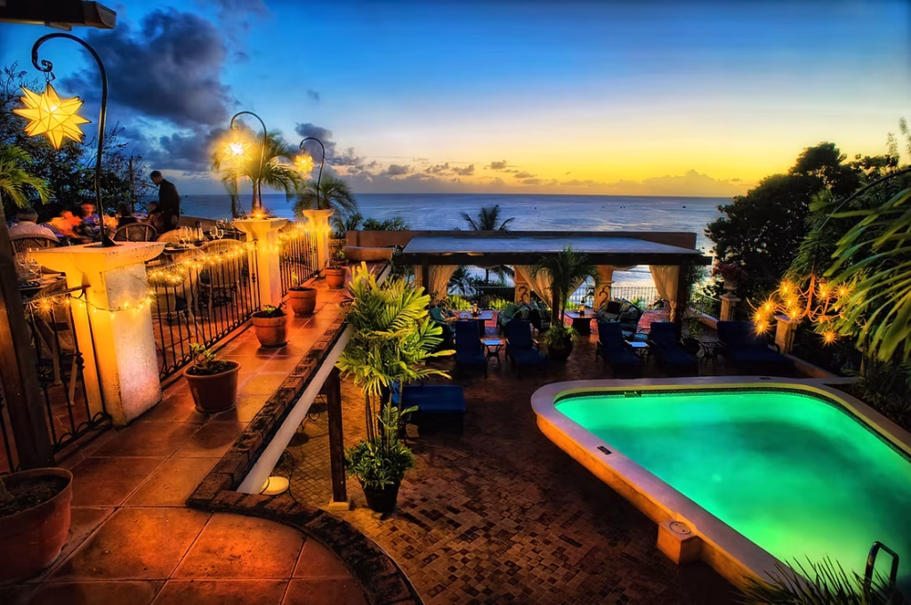 restaurant balcony overlooking a glowing pool at night time
