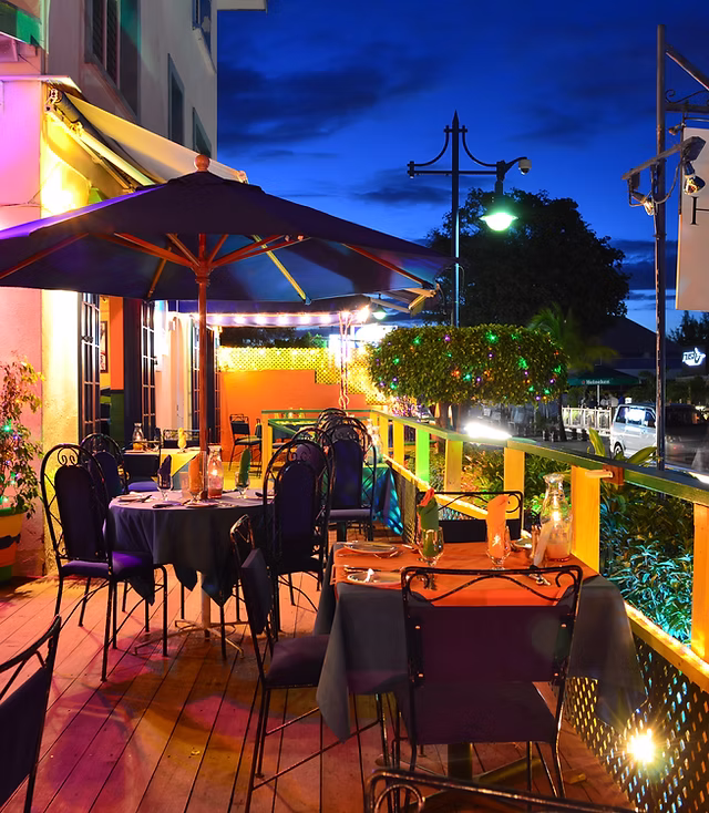 colourful restaurant scene at night with a set of chairs under a parasol