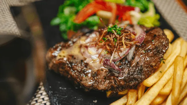 steak and fries with salad on the side and caramelised onions on top