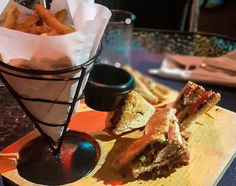 fries in a cone and sandwiches cut in a triangle shape on a wooden board