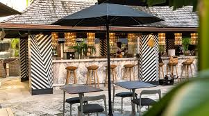 bar in the background with black parasol and seats on a table