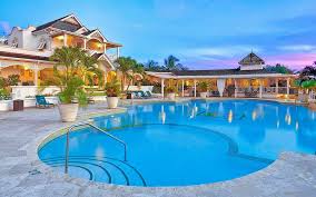 big mansion like building with a pool in front at sunset with plants around as decoration