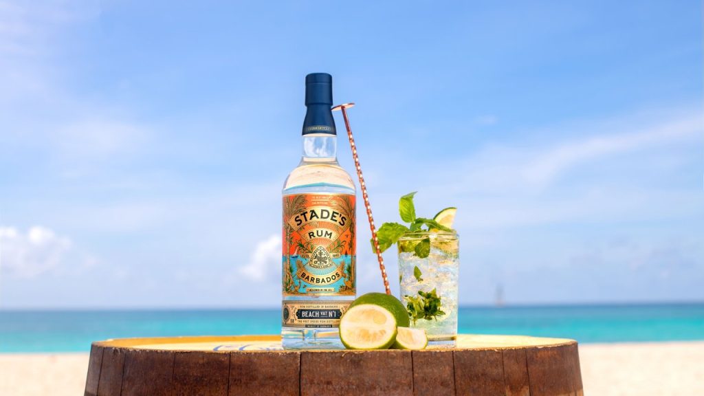 rum in front of a beach with a glass on top of a barrel
